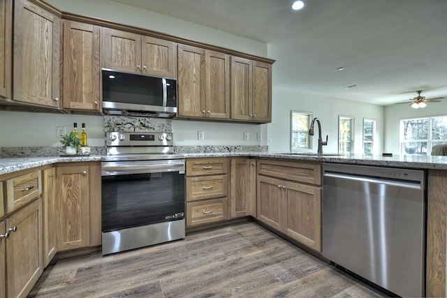 kitchen featuring appliances with stainless steel finishes, sink, dark wood-type flooring, and light stone counters