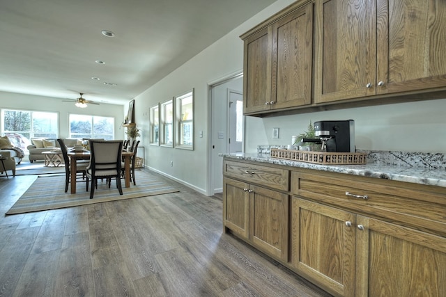 kitchen featuring light stone counters, hardwood / wood-style floors, and ceiling fan