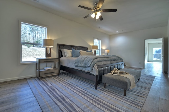 bedroom with hardwood / wood-style flooring, ceiling fan, and multiple windows