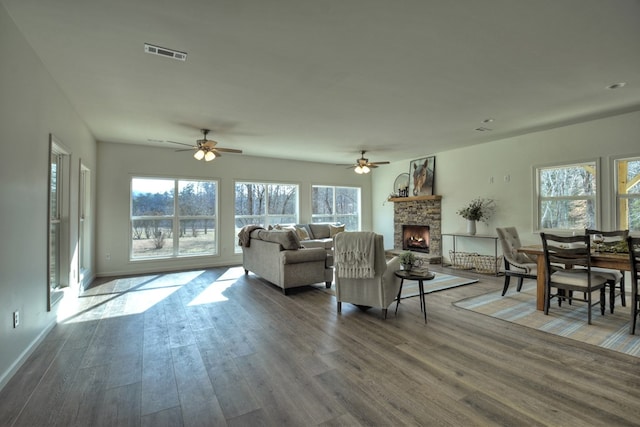 living room with a healthy amount of sunlight, a stone fireplace, and dark wood-type flooring