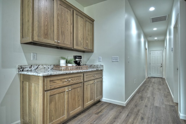 interior space with light stone counters and hardwood / wood-style floors