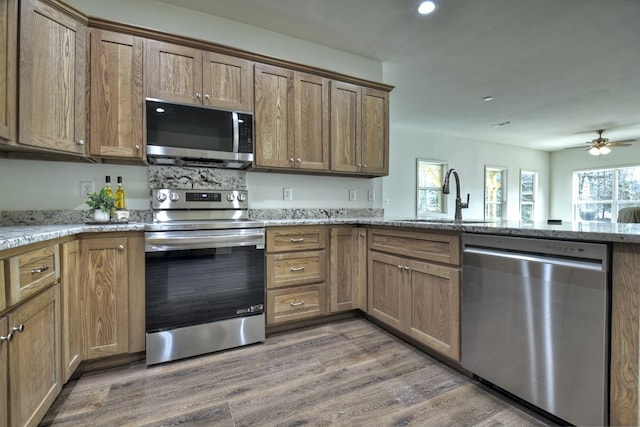 kitchen featuring appliances with stainless steel finishes, sink, light stone counters, and dark hardwood / wood-style floors