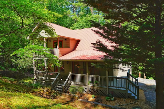 chalet / cabin featuring a porch, metal roof, and a balcony