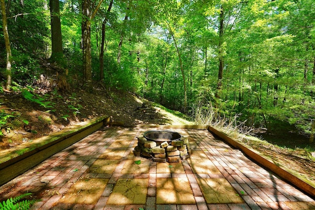 wooden deck with a fire pit, a patio, and a forest view