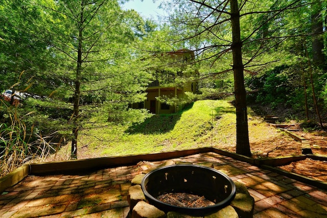 wooden terrace with an outdoor fire pit and a wooded view