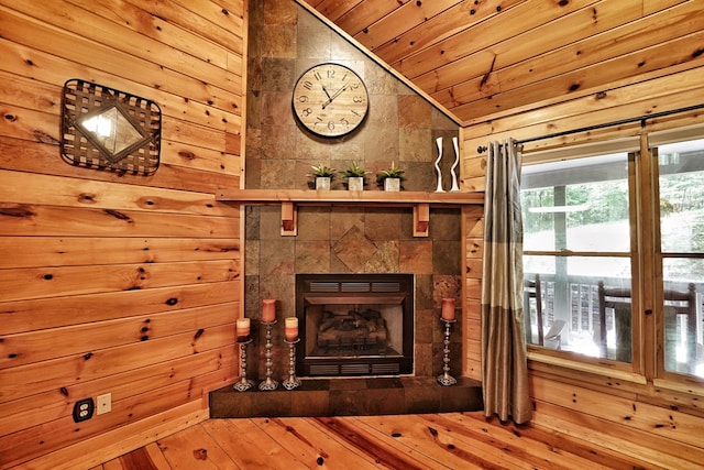 detailed view of wood ceiling, a tiled fireplace, wooden walls, and wood finished floors