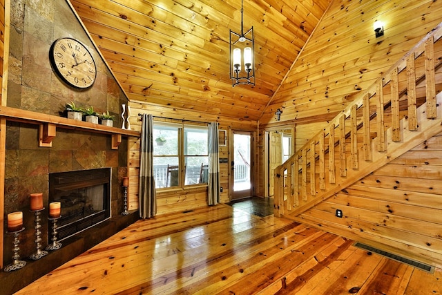 unfurnished living room featuring wood-type flooring, wooden ceiling, stairway, a tile fireplace, and high vaulted ceiling