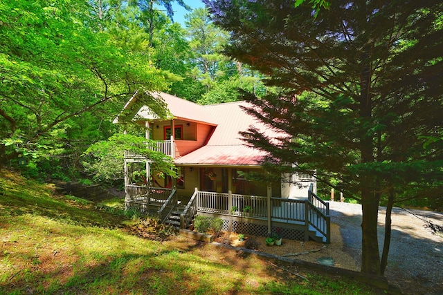 view of front of home featuring covered porch, a balcony, and metal roof
