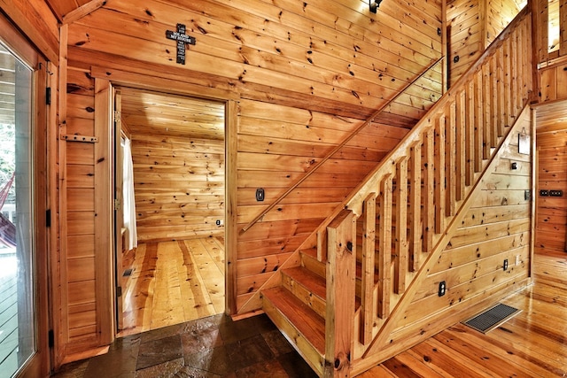 stairway featuring wood walls and stone finish floors