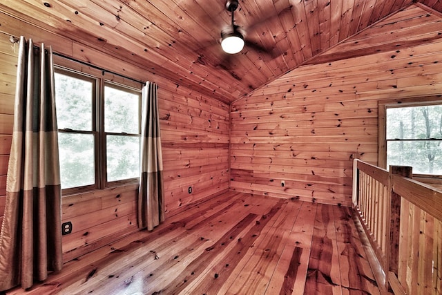 additional living space with lofted ceiling, wood walls, wooden ceiling, and hardwood / wood-style floors