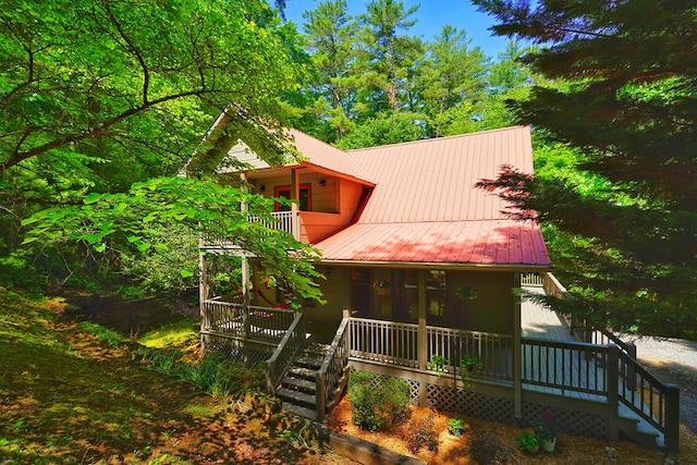 rear view of property with a balcony, metal roof, and covered porch