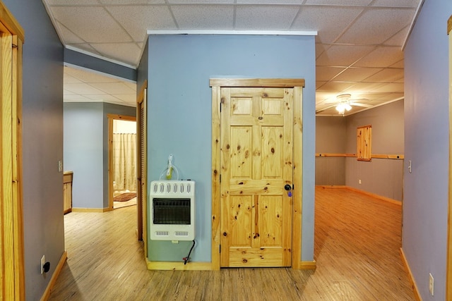 corridor featuring heating unit, a paneled ceiling, baseboards, and wood finished floors