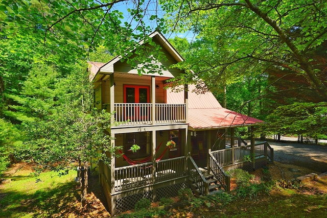view of front facade with a balcony, metal roof, french doors, and a porch