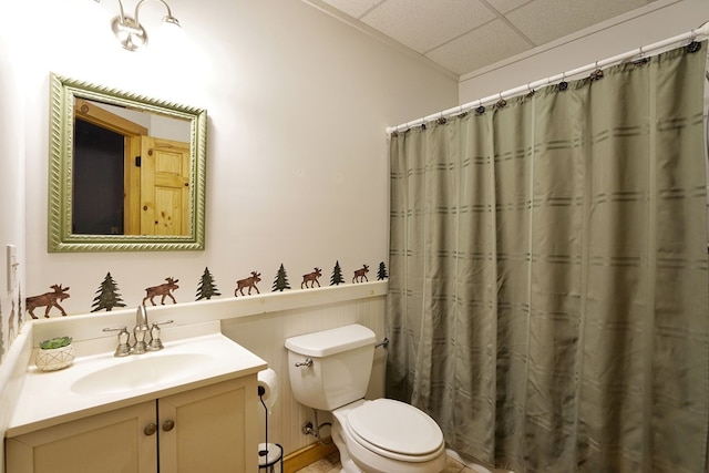 bathroom featuring a drop ceiling, toilet, vanity, and curtained shower