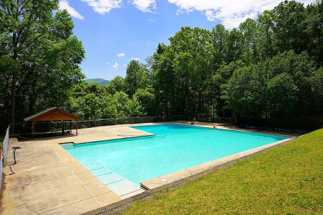 view of swimming pool featuring a gazebo, a patio, and a view of trees