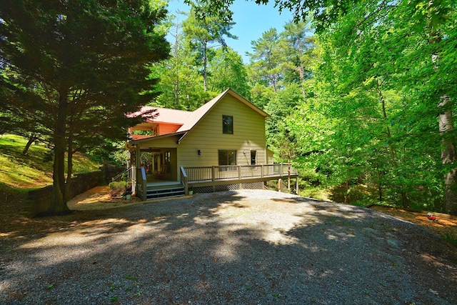 back of house featuring driveway and a deck