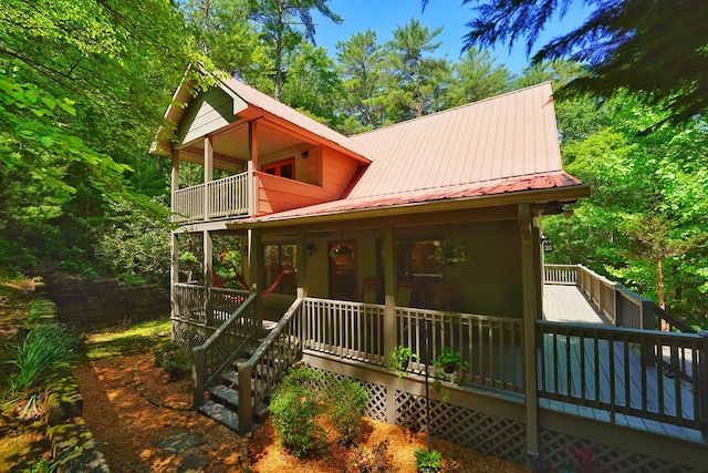 view of front facade featuring a balcony, metal roof, and a wooden deck