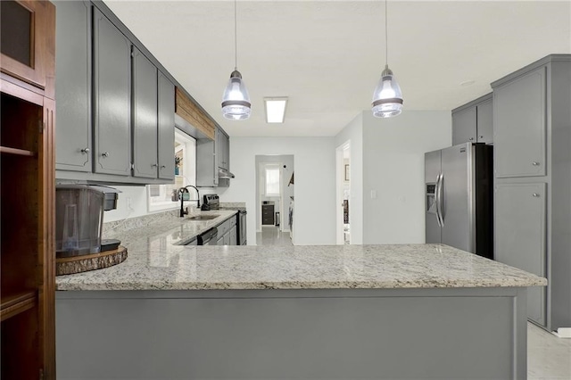 kitchen featuring pendant lighting, appliances with stainless steel finishes, kitchen peninsula, and sink