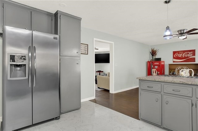 kitchen featuring gray cabinets, pendant lighting, ceiling fan, and stainless steel fridge with ice dispenser