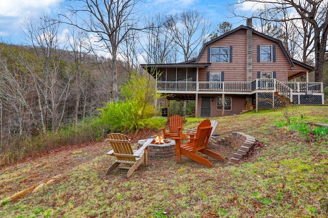 back of property with a fire pit and a wooden deck