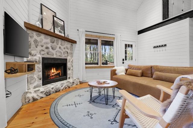 living room with a fireplace, high vaulted ceiling, and wood-type flooring