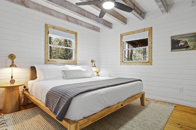 bedroom with multiple windows, hardwood / wood-style floors, ceiling fan, and beam ceiling