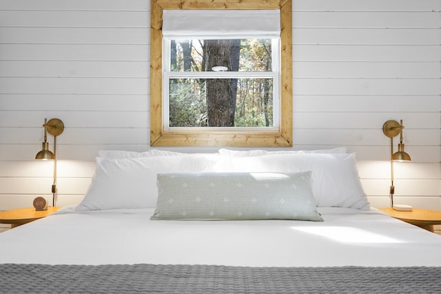 bedroom featuring wooden walls and multiple windows