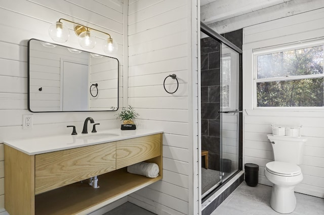 bathroom featuring vanity, a shower with shower door, and wooden walls