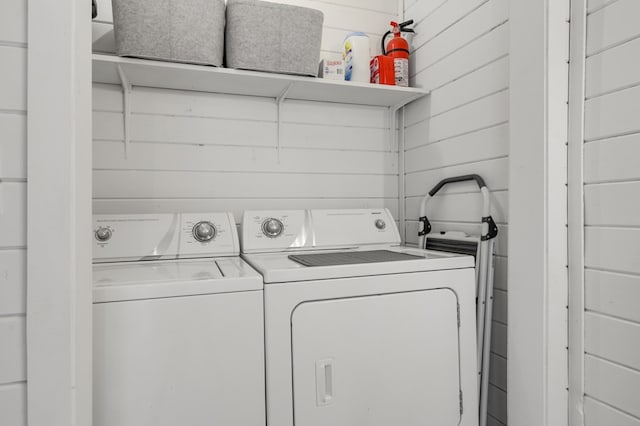 washroom with washing machine and clothes dryer and wood walls