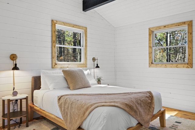 bedroom featuring wood walls, lofted ceiling with beams, and wood-type flooring