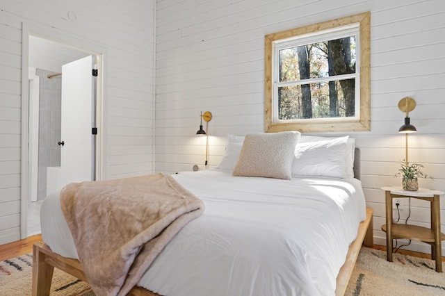 bedroom with wooden walls and light hardwood / wood-style floors