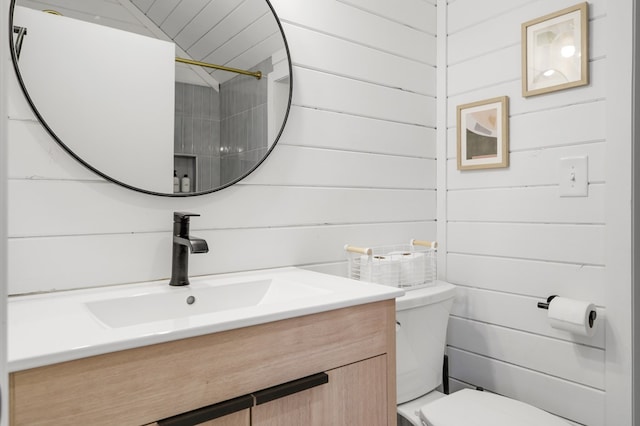 bathroom with vanity, wood walls, and toilet