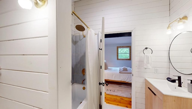 bathroom featuring vanity, shower / bath combo with shower curtain, and wood walls