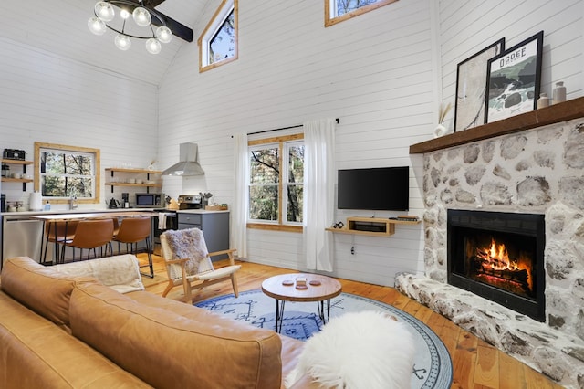 living room featuring wood-type flooring, a large fireplace, high vaulted ceiling, and wood walls