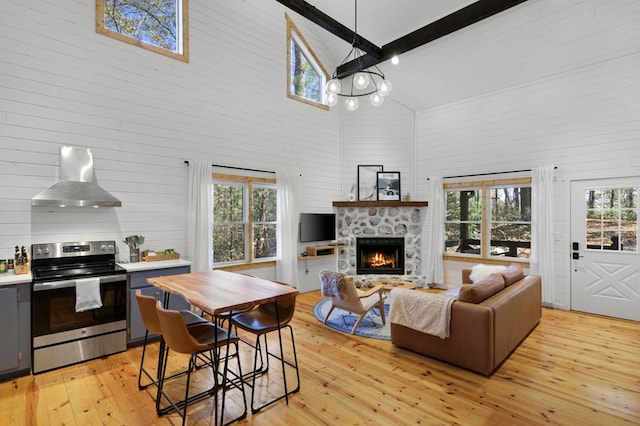 living room with beamed ceiling, light hardwood / wood-style floors, high vaulted ceiling, and a stone fireplace