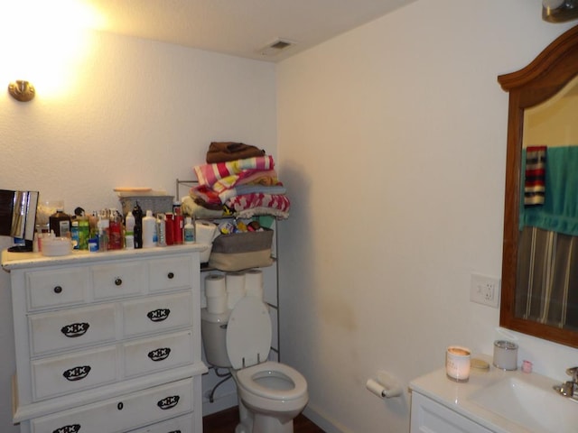 half bathroom with visible vents, vanity, and toilet