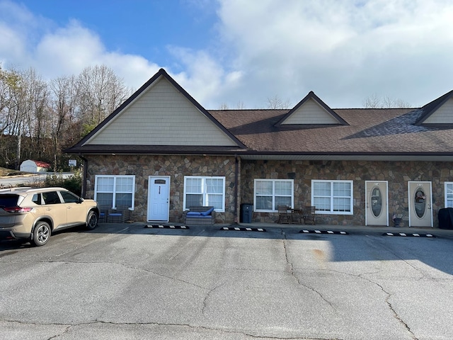 view of front of house featuring stone siding and uncovered parking