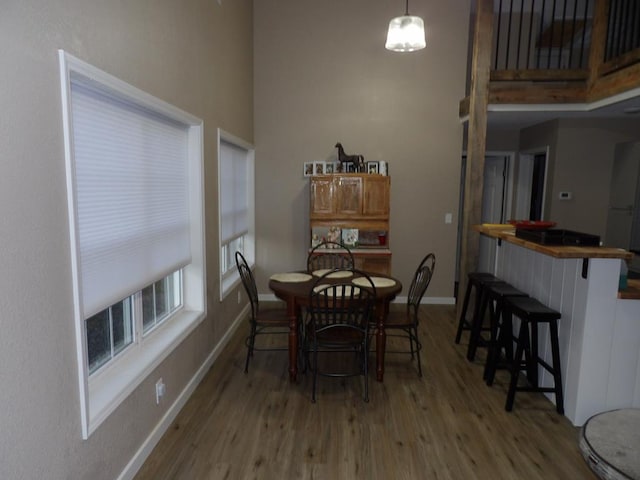 dining area with a towering ceiling, light wood-style flooring, and baseboards