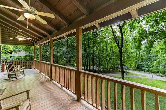 wooden terrace featuring ceiling fan, a yard, and a porch