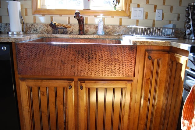 kitchen featuring a sink, black dishwasher, brown cabinetry, and light countertops