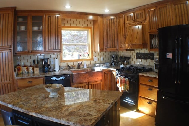 kitchen featuring premium range hood, black appliances, and brown cabinetry