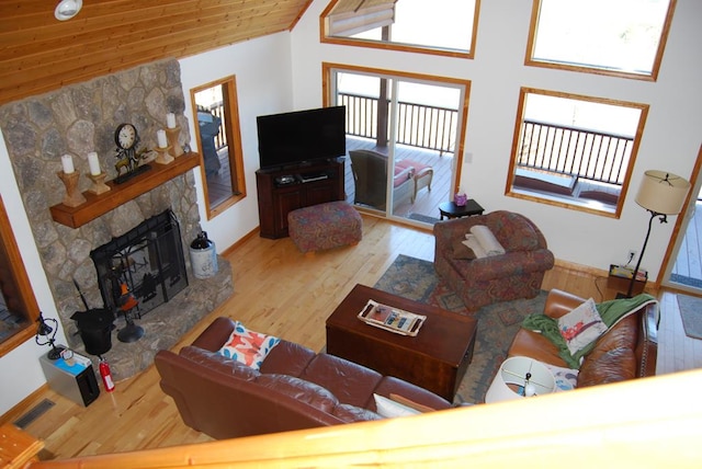 living area with wood finished floors, visible vents, high vaulted ceiling, a stone fireplace, and wooden ceiling