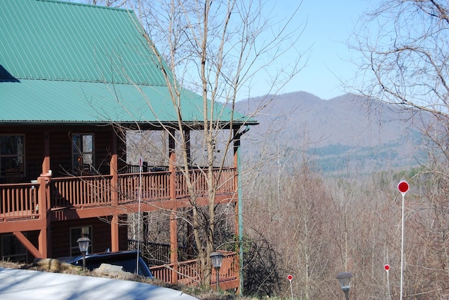 view of side of property with faux log siding, a deck with mountain view, and metal roof