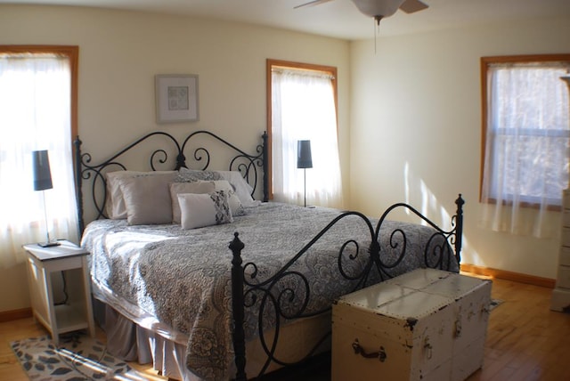 bedroom featuring light wood finished floors, multiple windows, and baseboards