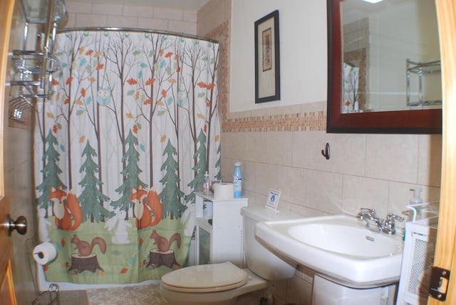 bathroom featuring toilet, curtained shower, tile walls, and a sink