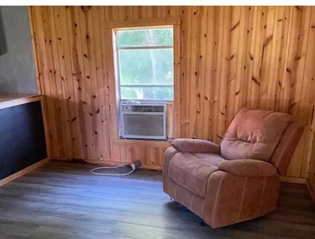 living area with dark hardwood / wood-style flooring, cooling unit, and wood walls