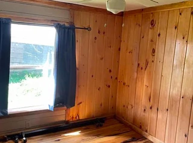 unfurnished room with a wealth of natural light, wooden walls, and wood-type flooring