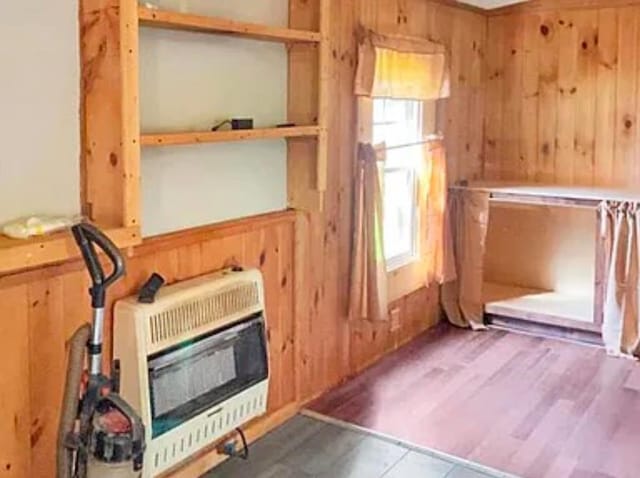 interior space with heating unit, wooden walls, and a healthy amount of sunlight