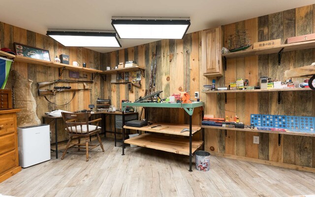 misc room featuring light hardwood / wood-style flooring, a workshop area, and wooden walls