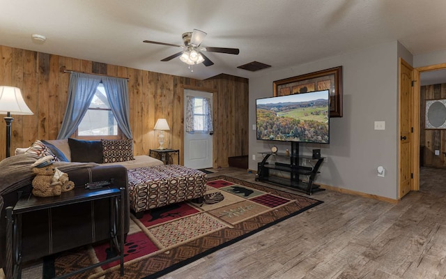 living room featuring wood walls, ceiling fan, and hardwood / wood-style floors